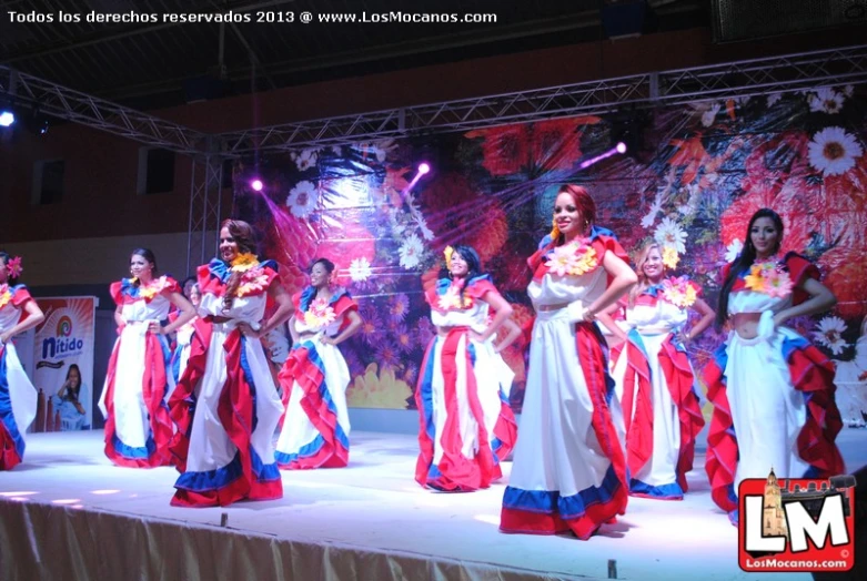 several beautiful women in different colored dresses on a stage