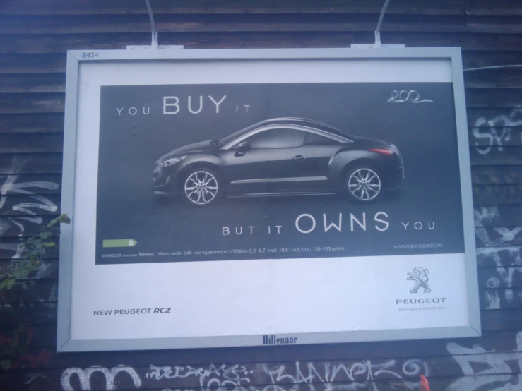 a sign with an advertit of a sports car that reads you buy it, but owns you