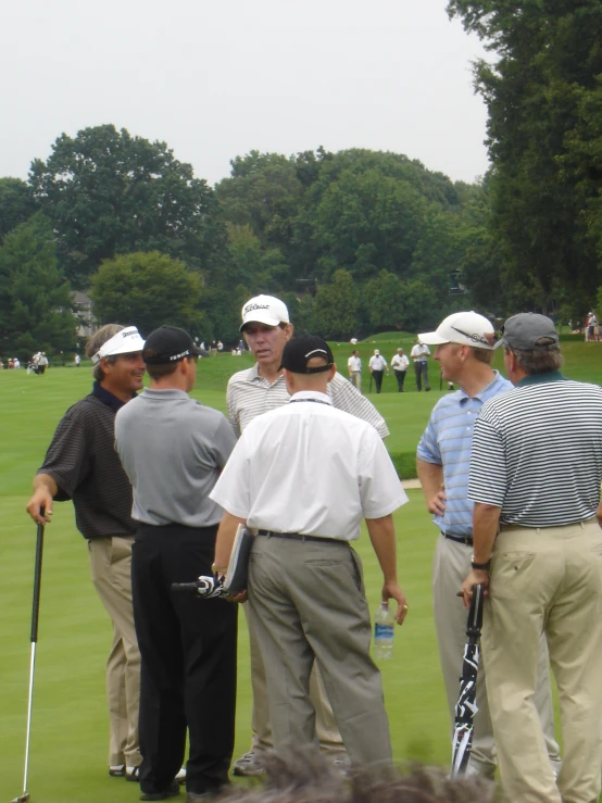 a group of men standing around each other on a grass field