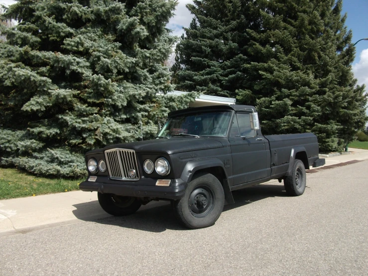 a black truck parked on the side of a road near some trees