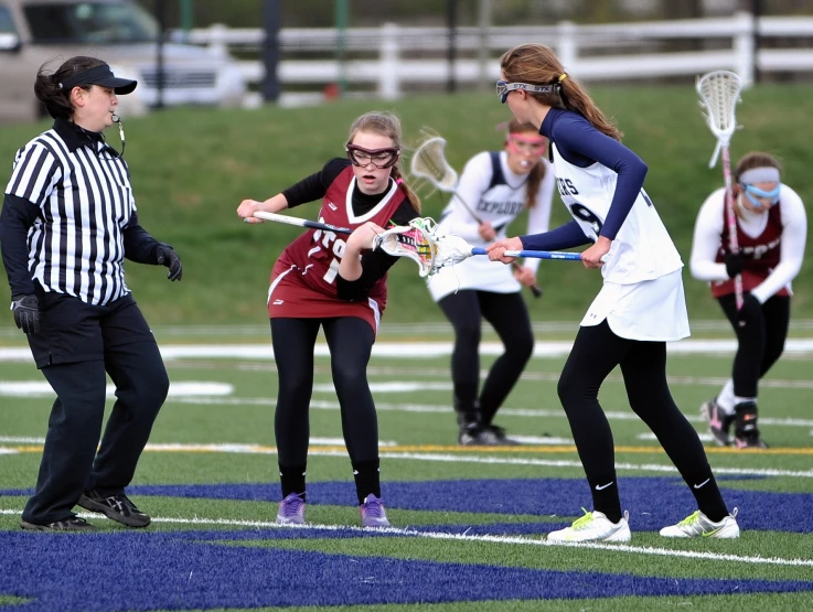 several girls playing lacrosse on the field