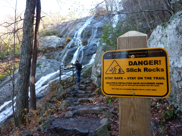 man with climbing gear in standing next to waterfall