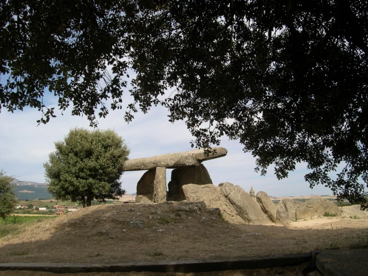 a large rock formation with a stone bench under a tree