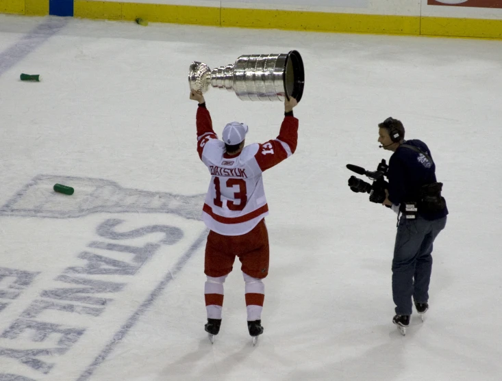 an official is holding a trophy while standing on a hockey rink