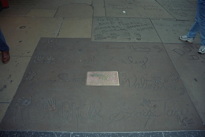 an inscription is in the sidewalk as people walk past it