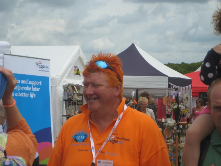 a man in an orange shirt stands near some booths