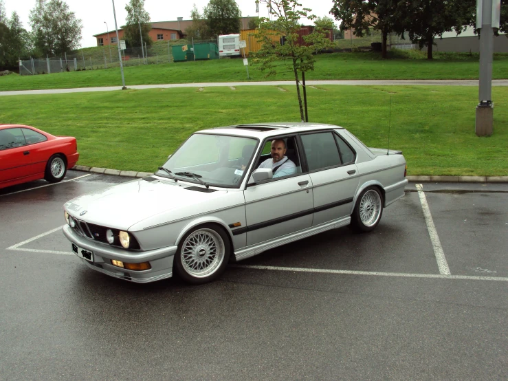 two cars sit in a parking lot, one with the door open