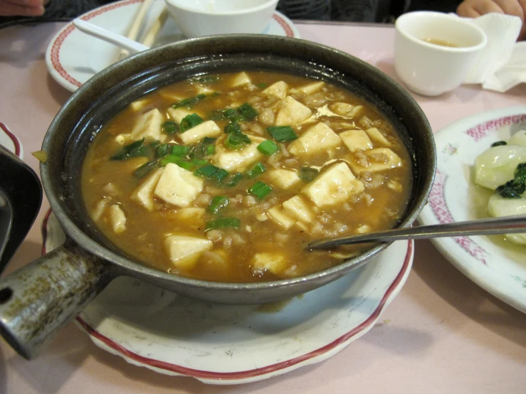 soup with tofu and some greens and a side dish