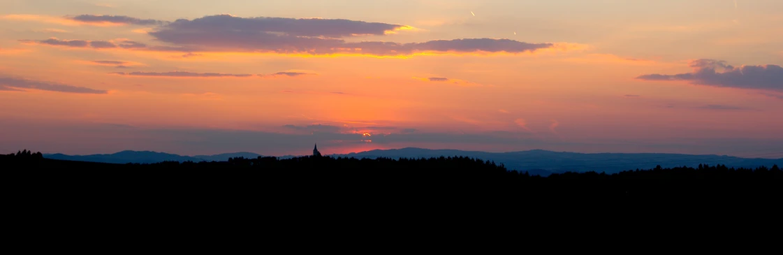 the sunset behind a mountain range on a cloudy day