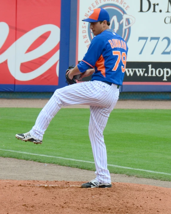 a baseball player in a blue and white uniform pitching a baseball