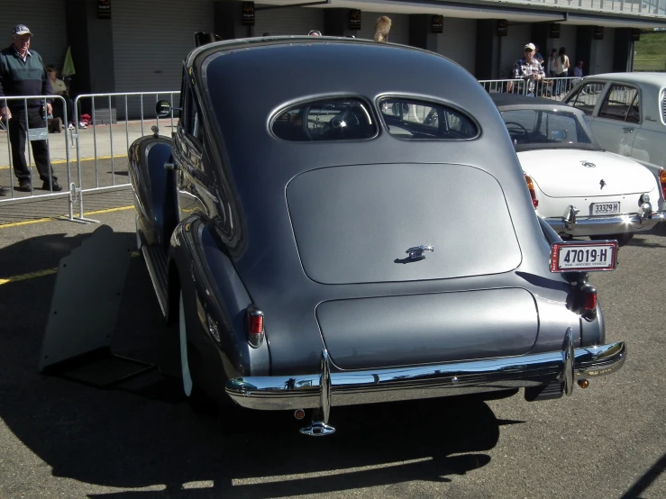 an old black car is parked in a lot