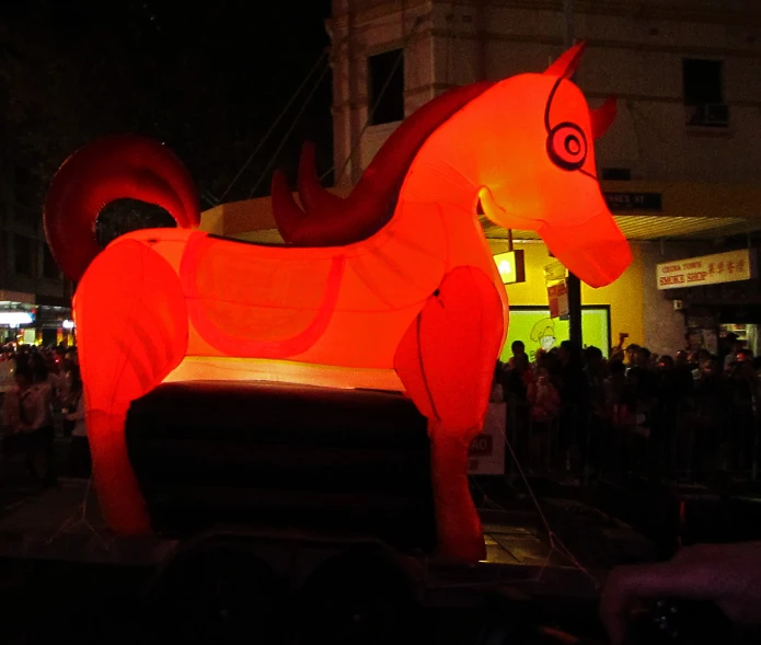 an illuminated horse on the ground near people