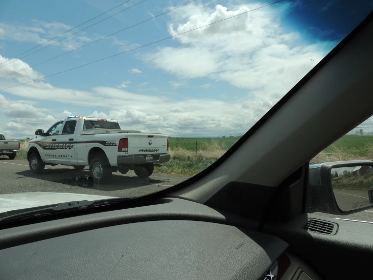 a white truck is traveling on a rural road