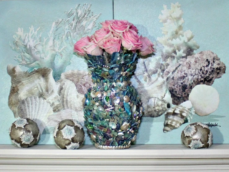 several seashells with pink roses in a vase