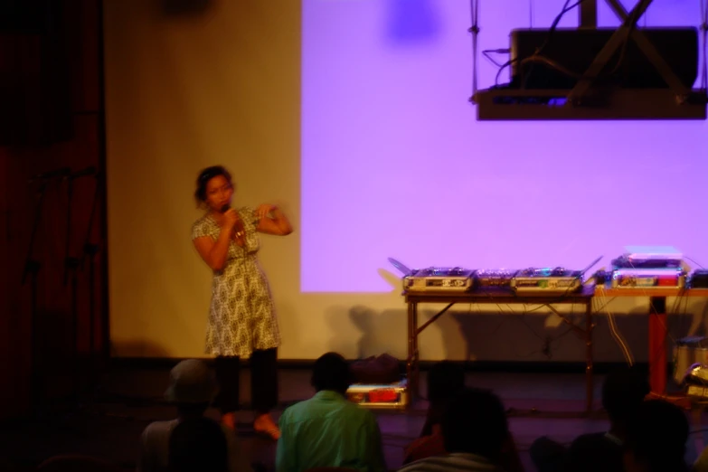 a woman stands in front of a purple wall on stage