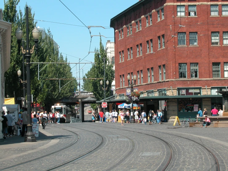 people standing on street with train tracks in the middle