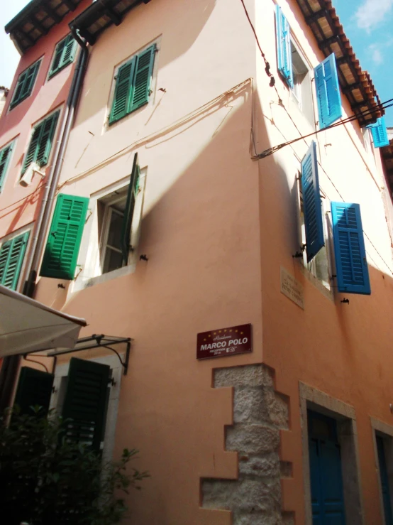 an older building has shutters open and green shutters