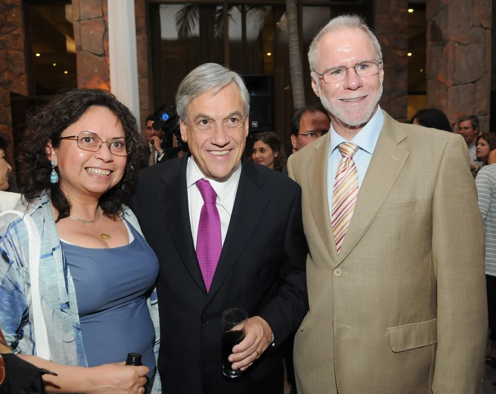 two men and a woman smile while standing together