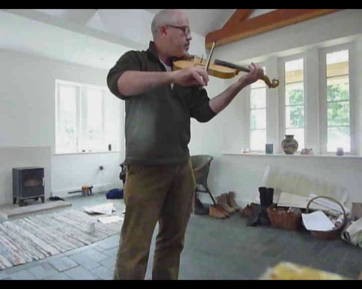 a man playing violin in a room with many items