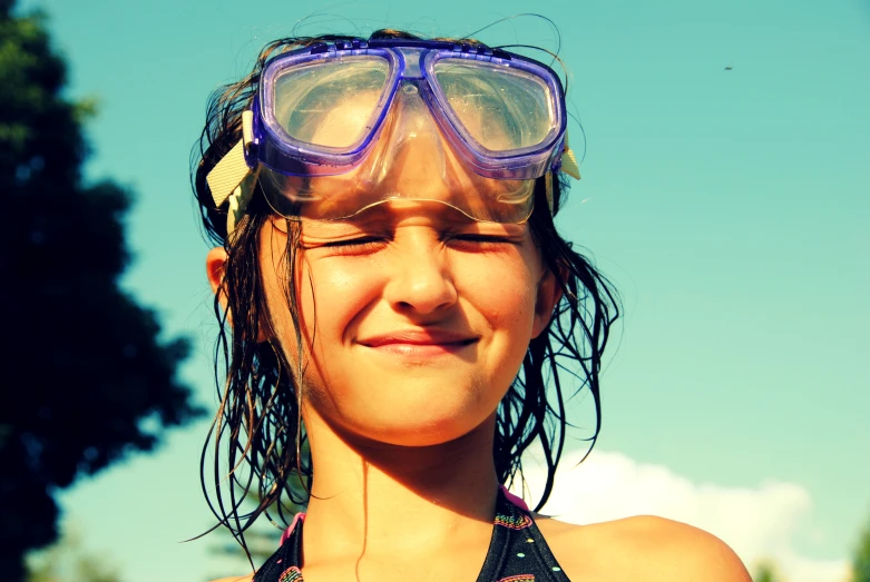 girl wearing purple goggles with blue sky in background