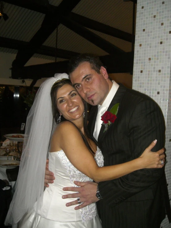 the bride and groom are cuddling under a wedding tent