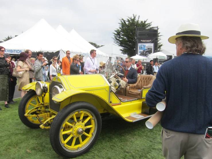 a yellow sports car with two men in it's side seats