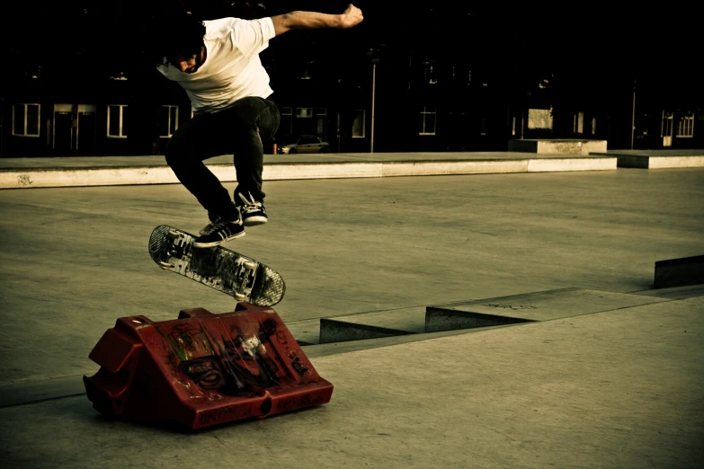 man jumping over a red luggage cart in the middle of a street