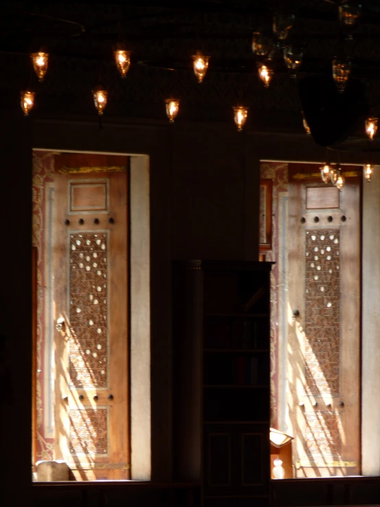 two ornate wooden doors and lights shining through