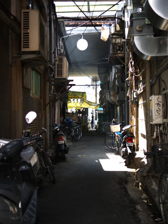 a narrow narrow city alleyway with parked motorcycles