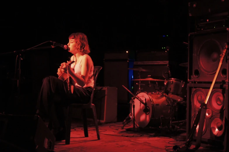 a woman is sitting at a chair on stage