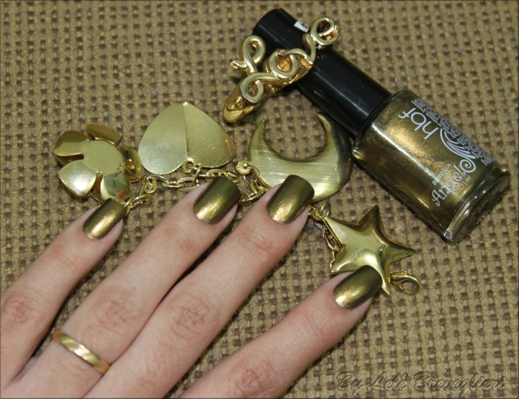 manicure nails with gold decorations next to a bottle of nail polish