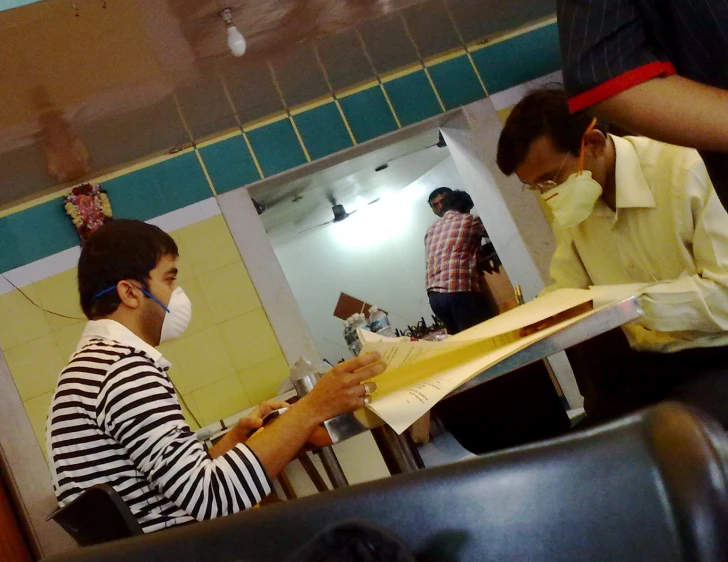 people standing around a dining room table with some paper