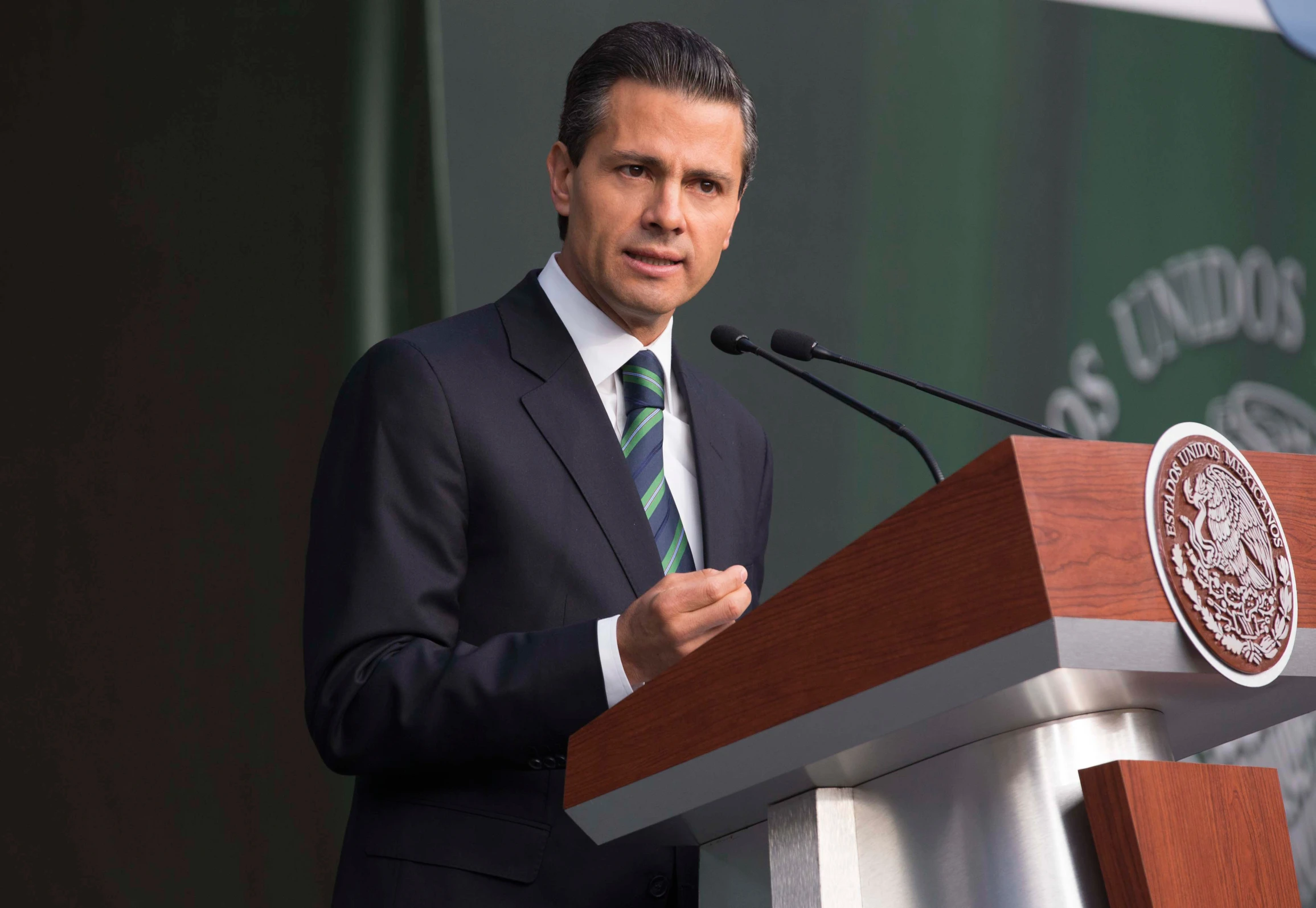 a man in a suit speaks behind a podium