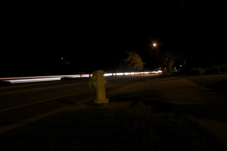 a fire hydrant in the dark with headlights shining on it