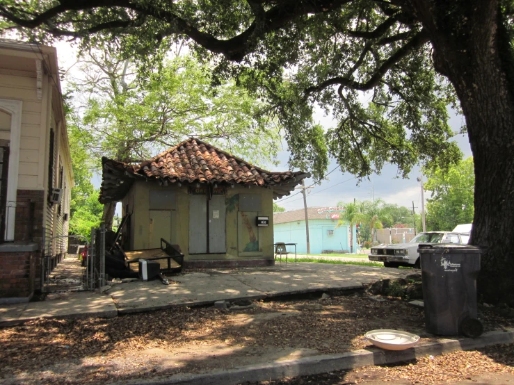 a wooden gazebo under a tree and a trash can