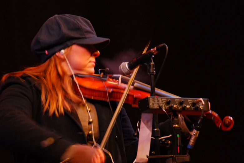 woman playing violin in front of microphone on stage