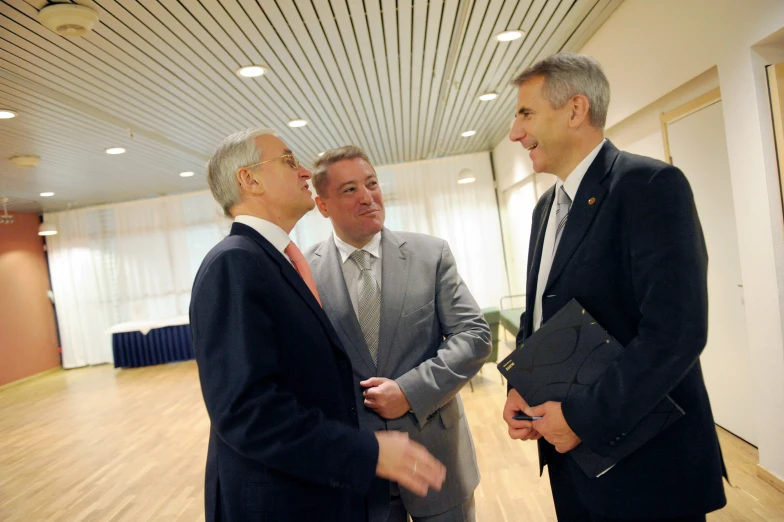 a group of four men wearing suits standing on a wooden floor