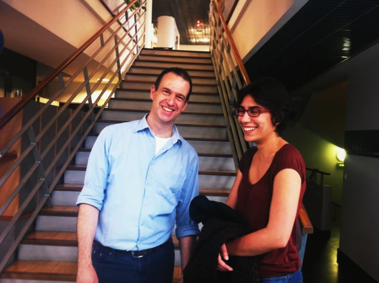 a man and woman smiling next to a staircase