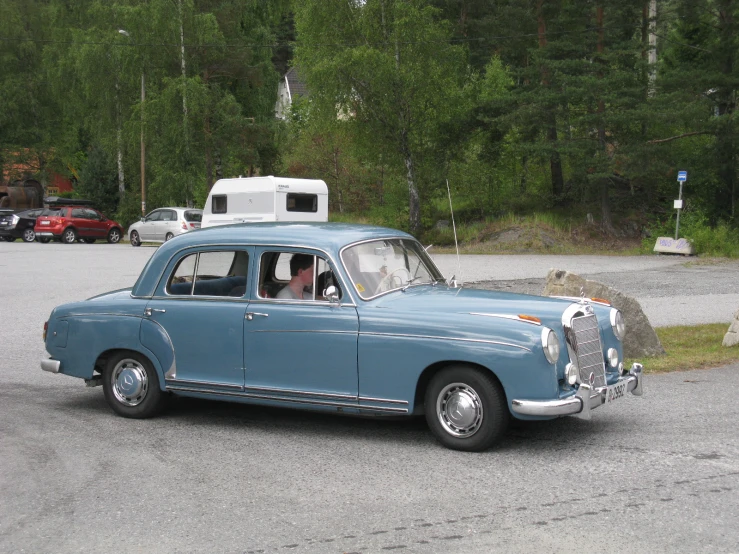 a blue car parked by some trees near a forest