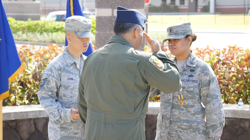 three military men standing near each other in a field