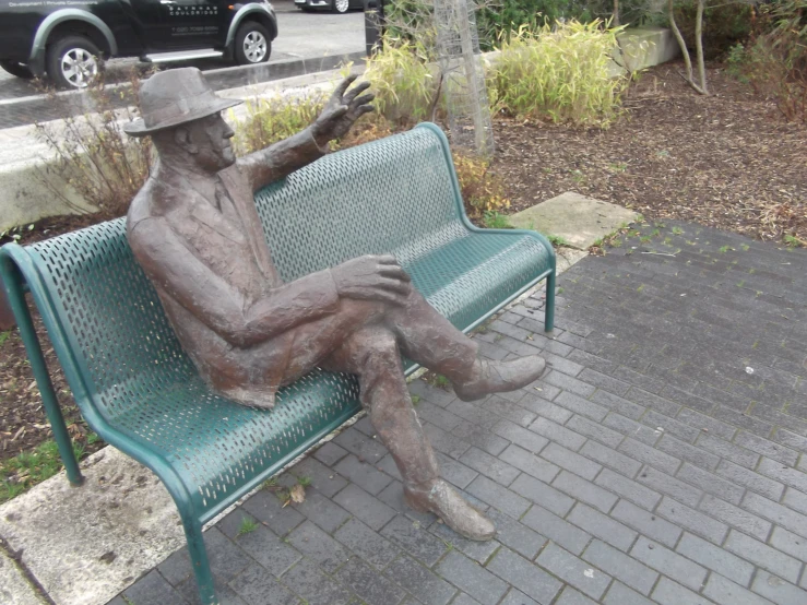the statue is sitting on a bench outside