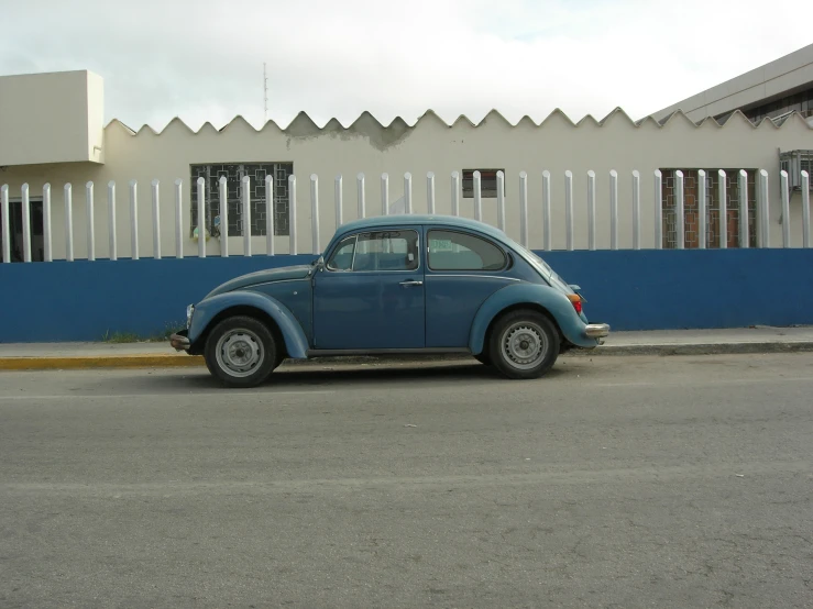 blue volkswagen beetle parked outside a white house