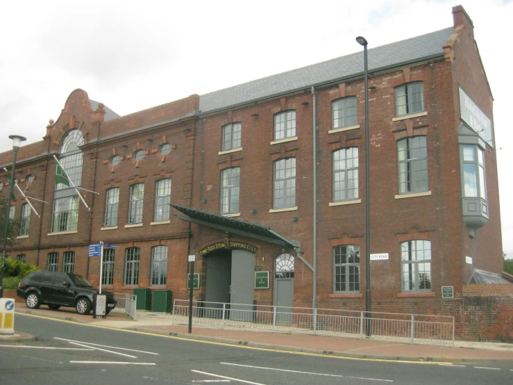 a car parked at the side of the road in front of a brick building