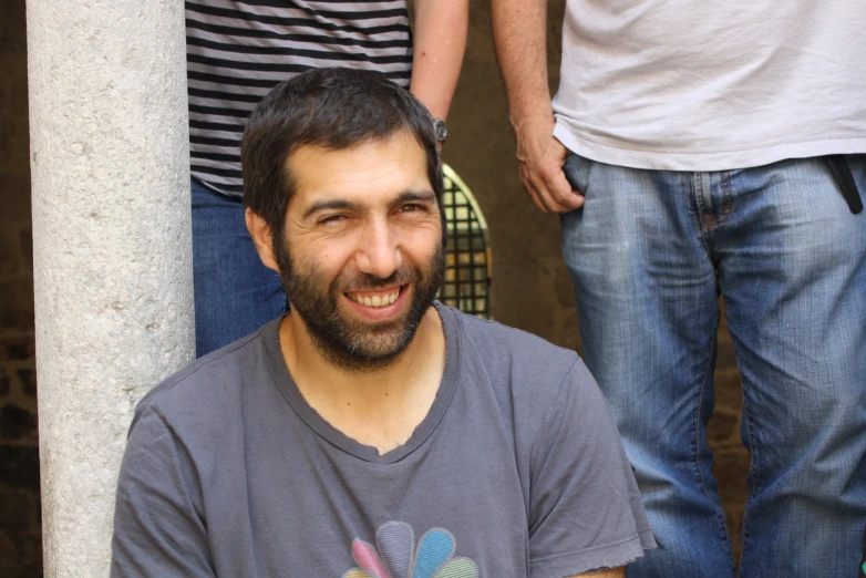 a man sitting down smiling and posing for the camera