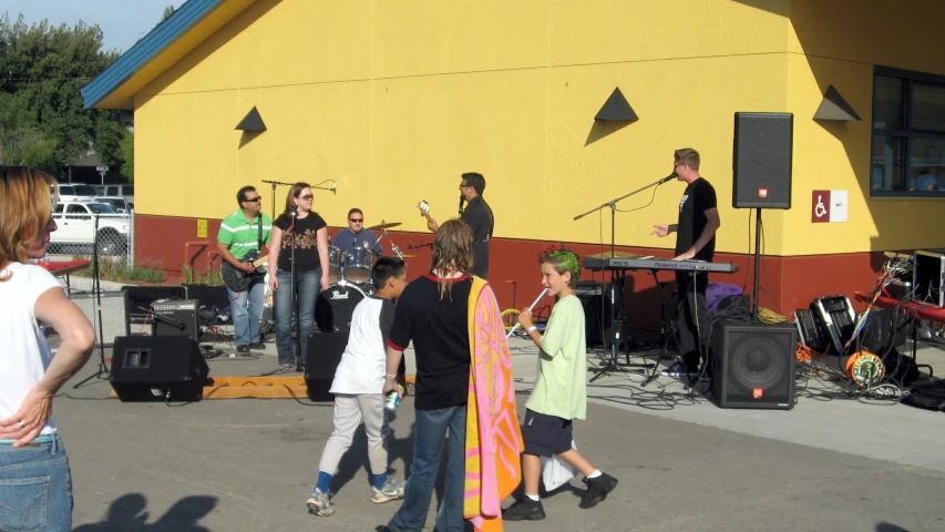 a group of young people in front of a yellow building