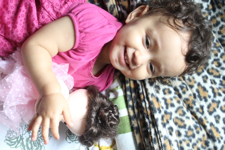 baby in pink dress smiling on animal print blanket