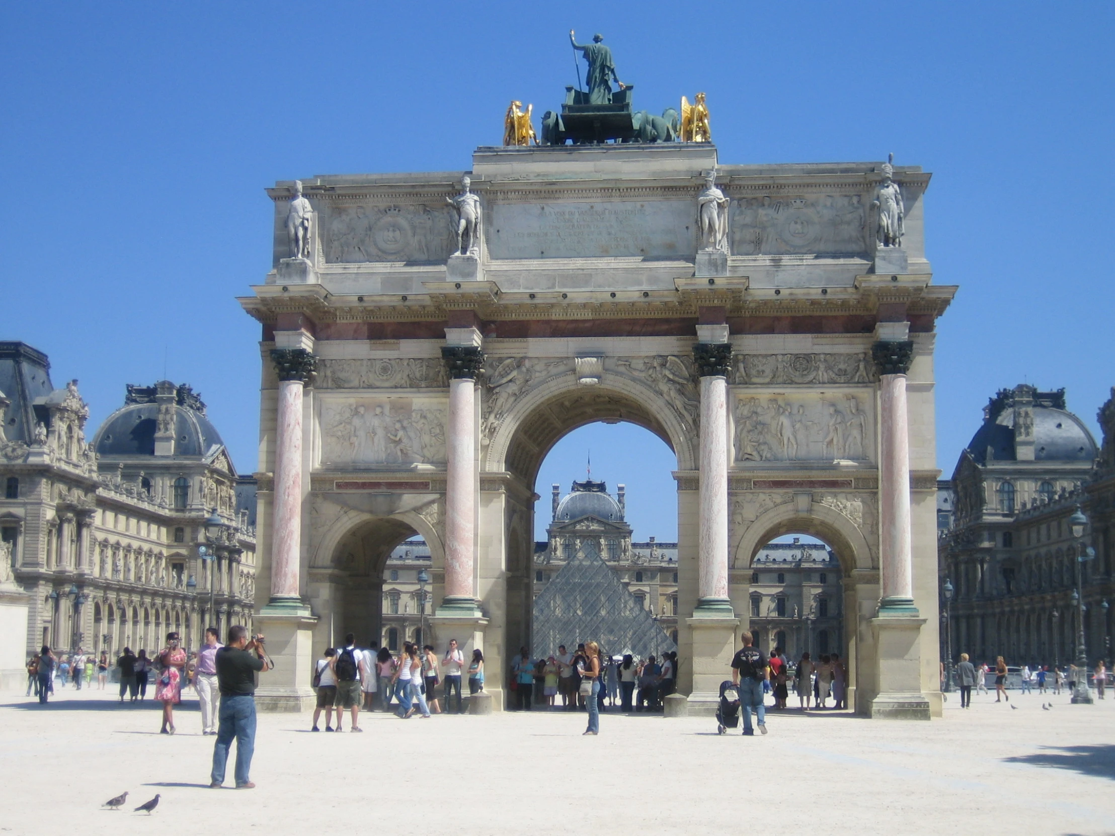 a busy city square with arches and people walking about