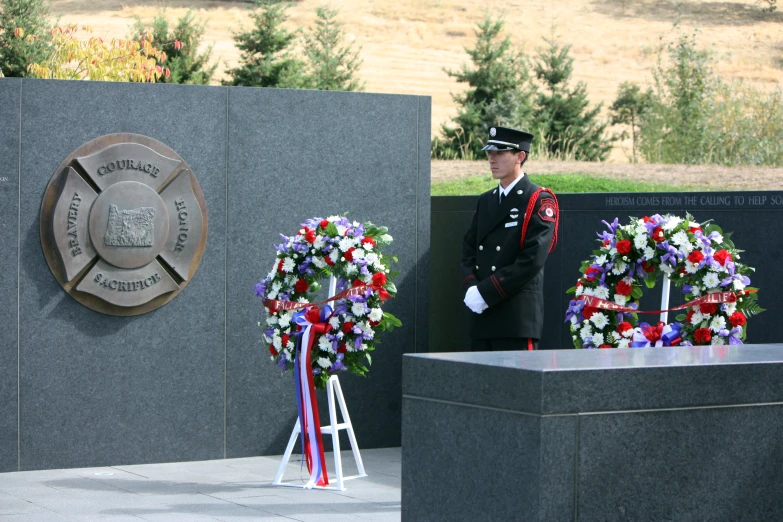 a military man in uniform standing next to two wreaths