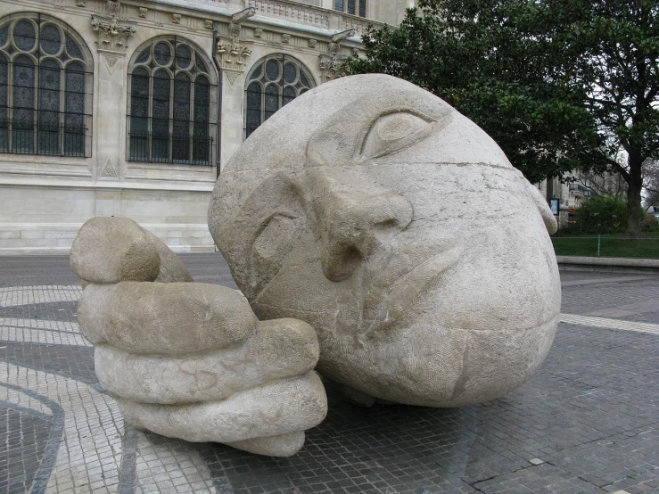 two gray rocks on the ground near some building