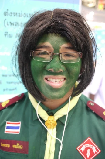 a young person wearing green paint and gold rings